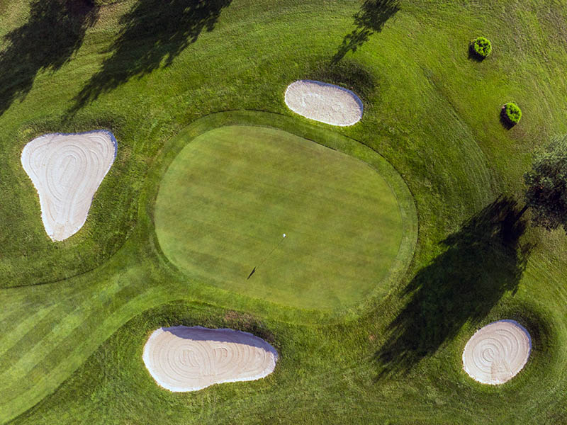 Aerial view of Hole 6 at Flatbush Golf Course in Littlestown, Pennsylvania, showing the green surrounded by multiple sand bunkers, fairway, rough, and tree shadows.
